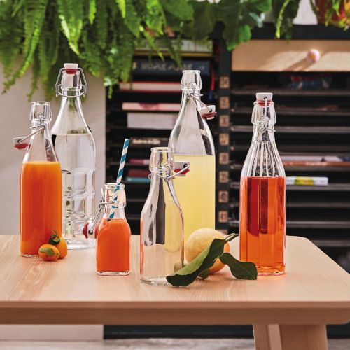 Sfeervolle setting met gevulde ronde beugelfles Giara 1 liter op tafel.